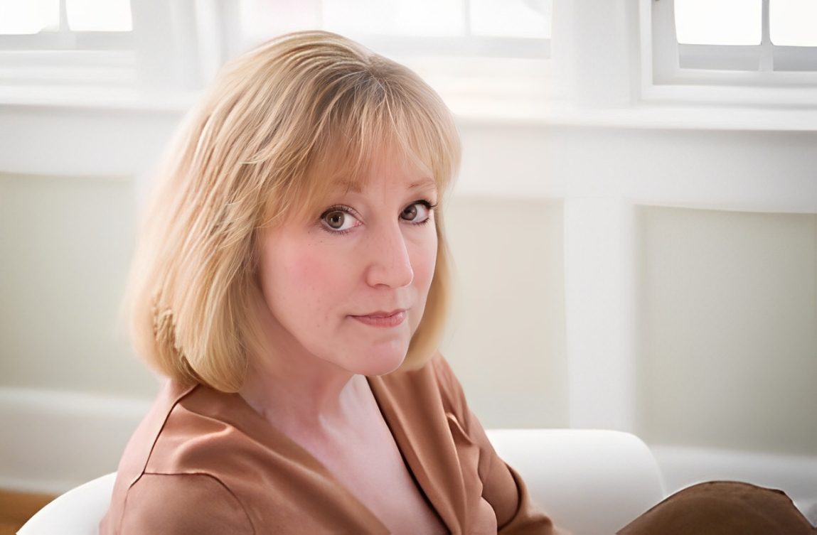 Woman sitting indoors, looking at camera.