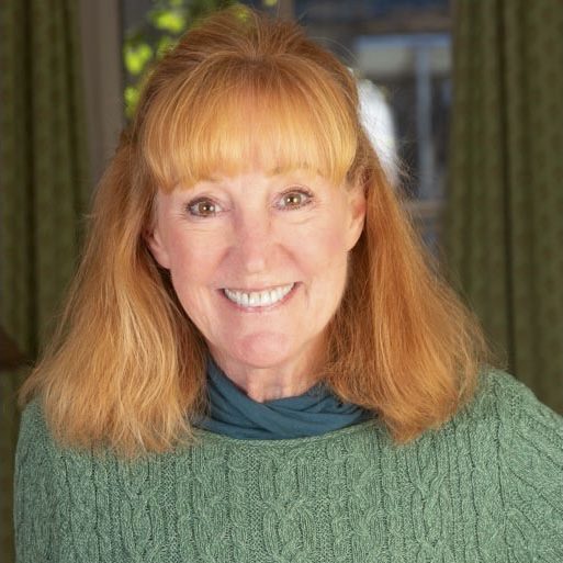 Smiling woman with red hair wearing a green sweater.